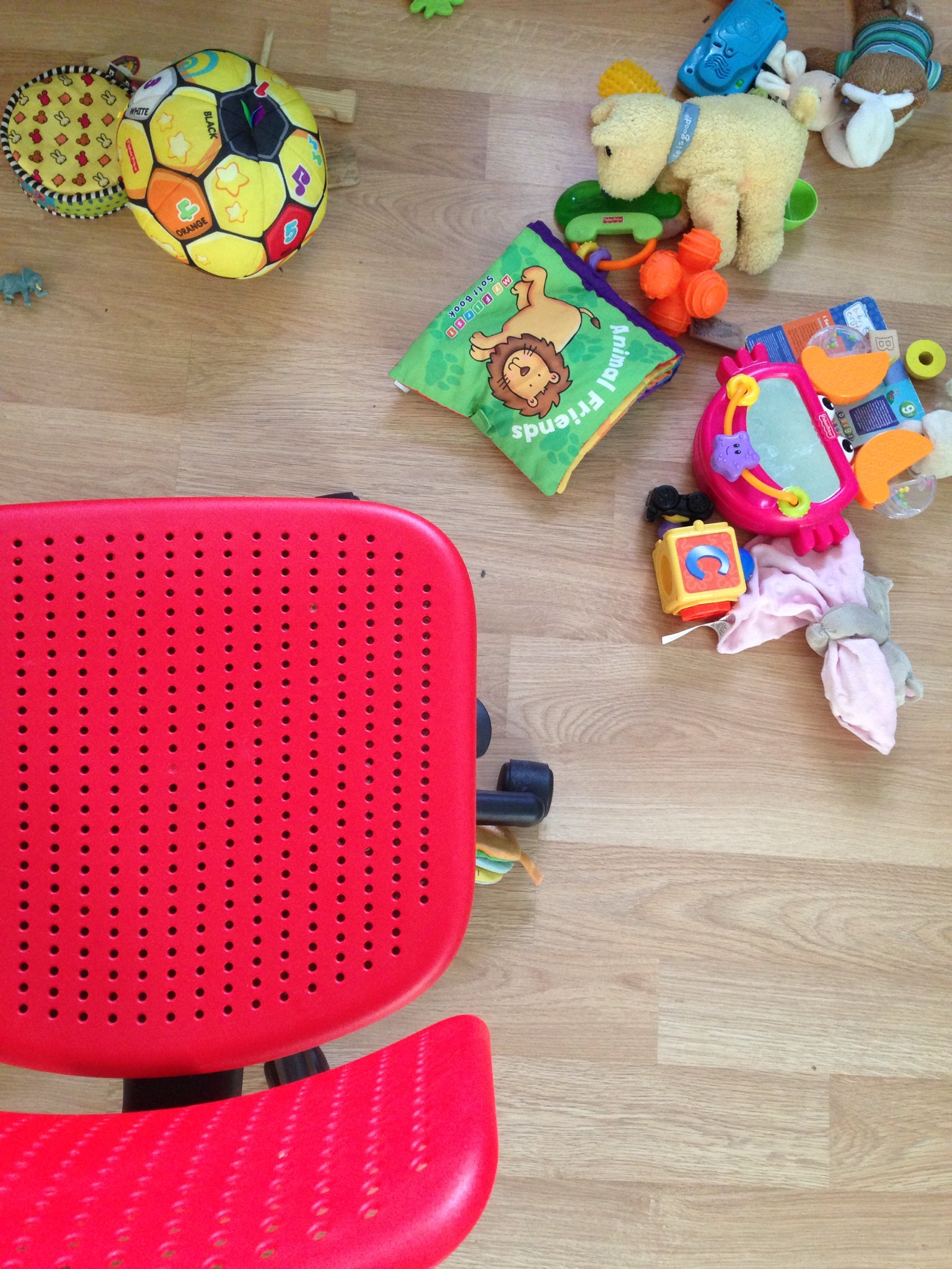 Red office chair and toys in the messy office of a self employed designer