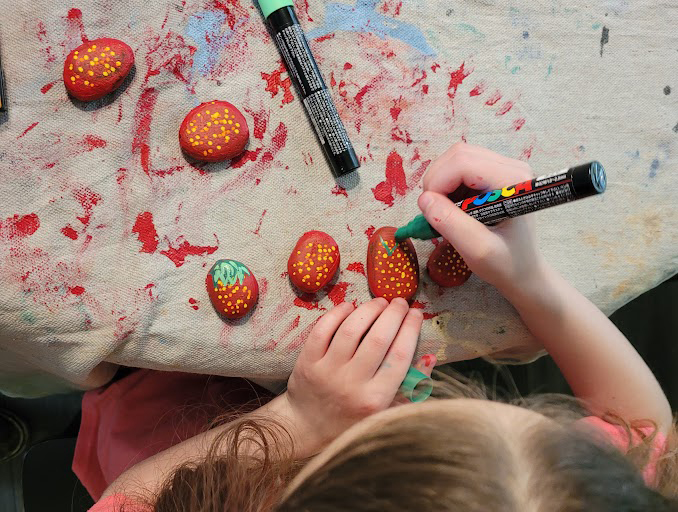 Painting strawberry rocks for the garden with poses paint markers